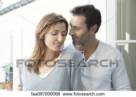 Couple embracing by open window View Large Photo Image Stock Photo - Couple embracing by open window. Fotosearch
