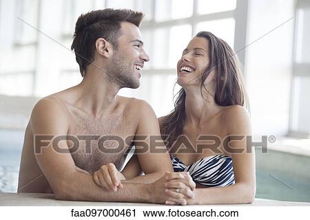 Stock Image - Couple relaxing together in indoor swimming pool. Fotosearch