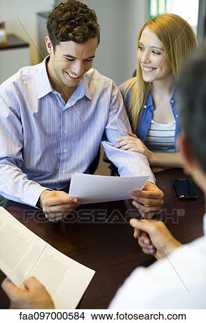 Picture - Couple reviewing paperwork in meeting with advisor. Fotosearch