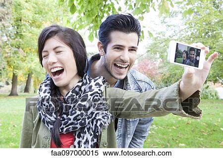 Couple taking self portrait with smartphone View Large Photo Image Stock Photography - Couple taking self portrait with smartphone. Fotosearch