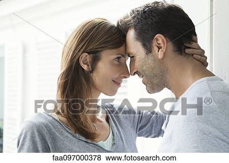 Stock Photo - Couple touching noses by window. Fotosearch