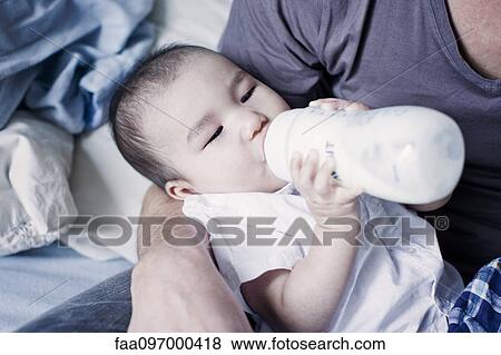 Stock Photo - Father feeding bottle feeding baby. Fotosearch