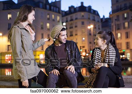 Stock Image - Friends hanging out together outdoors at night. Fotosearch
