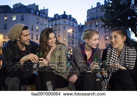 Picture - Friends having beer together outdoors. Fotosearch