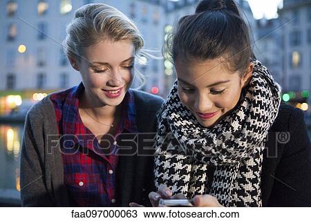 Friends looking at smartphone together View Large Photo Image Stock Image - Friends looking at smartphone together. Fotosearch