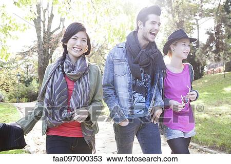 Friends walking together in park View Large Photo Image Stock Image - Friends walking together in park. Fotosearch