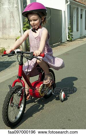 Girl riding bicycle with training wheels View Large Photo Image Stock Photograph - Girl riding bicycle with training wheels. Fotosearch