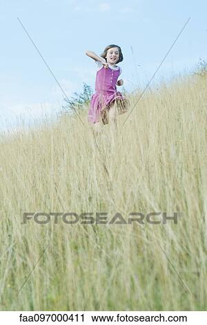Stock Image - Girl running through tall grass. Fotosearch