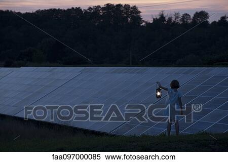 Girl standing in front of solar panels at twilight with old-fashioned lantern in hand View Large Photo Image Stock Photography - Girl standing in front of solar panels at twilight with old-fashioned lantern in hand. Fotosearch