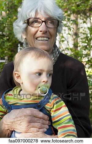 Stock Photo - Grandmother holding young grandson on lap outdoors. Fotosearch