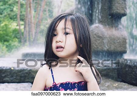 Stock Image - Little girl by water fountain, portrait. Fotosearch
