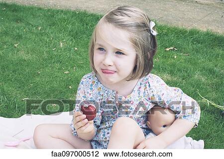 Stock Image - Little girl eating macaroon. Fotosearch