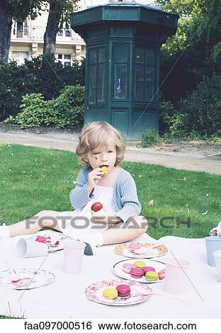 Stock Photograph - Little girl eating macaroon. Fotosearch