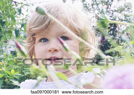 Stock Image - Little girl in flower garden, portrait. Fotosearch