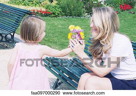 Little girl presenting mother with flower bouquet View Large Photo Image Stock Image - Little girl presenting mother with flower bouquet. Fotosearch
