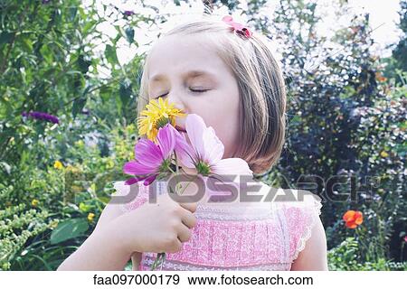 Little girl smelling flower View Large Photo Image Stock Photo - Little girl smelling flower. Fotosearch