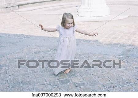 Stock Image - Little girl with arms outstretched playing outdoors. Fotosearch