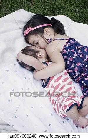 Stock Image - Little girl with baby brother lying on blanket outdoors. Fotosearch