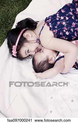 Stock Image - Little girl with baby brother lying on blanket outdoors. Fotosearch