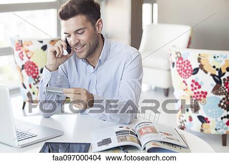 Man at home making credit card purchase over the phone View Large Photo Image Picture - Man at home making credit card purchase over the phone. Fotosearch