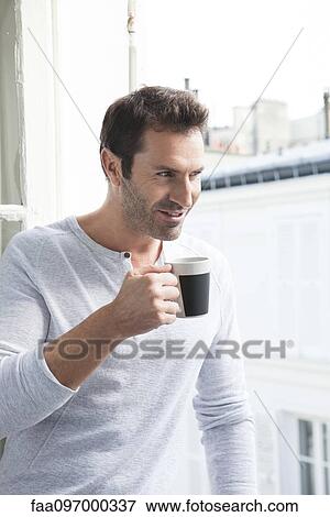 Man looking out of window with mug in hand View Large Photo Image Stock Photo - Man looking out of window with mug in hand. Fotosearch