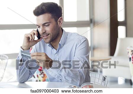 Stock Image - Man making credit card purchase over the phone. Fotosearch