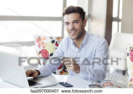Stock Photo - Man preparing to make online purchase using credit card. Fotosearch