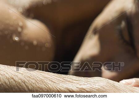 Stock Image - Man sunbathing, focus on wet forearm. Fotosearch
