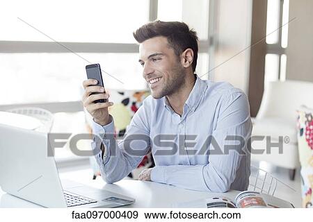 Stock Photo - Man with expression of happiness looking at smartphone. Fotosearch