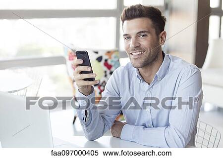 Stock Photography - Man with look of satisfaction holding smartphone. Fotosearch