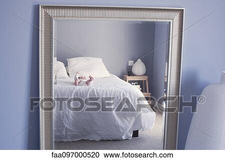 Stock Image - Mirror reflection of baby lying on bed. Fotosearch
