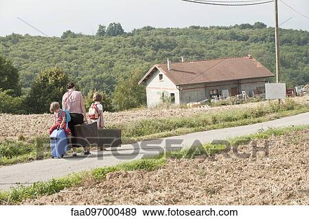 Mother and children wandering through countryside, dragging suitcases behind them View Large Photo Image Stock Photo - Mother and children wandering through countryside, dragging suitcases behind them. Fotosearch