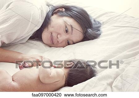 Stock Image - Mother with baby on bed, portrait. Fotosearch