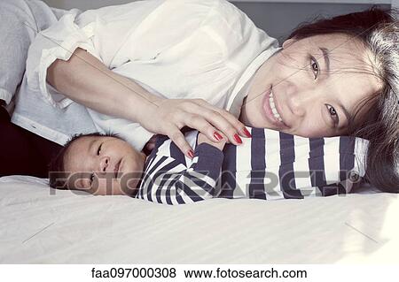 Mother with baby on bed, portrait View Large Photo Image Stock Photo - Mother with baby on bed, portrait. Fotosearch