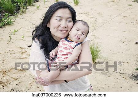 Stock Photograph - Mother with infant son outdoors, portrait. Fotosearch