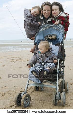 Stock Image - Mother with three children at the beach. Fotosearch