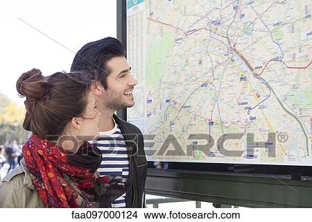 Tourist couple looking at outdoor city map at tourist information station View Large Photo Image Picture - Tourist couple looking at outdoor city map at tourist information station. Fotosearch