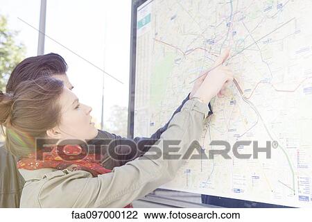 Stock Image - Tourist couple looking at outdoor city map at tourist information station. Fotosearch