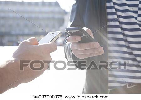 Stock Photograph - Two people exchanging information via smartphone. Fotosearch