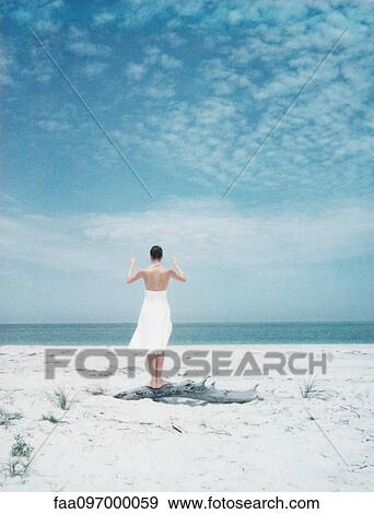 Woman balancing on driftwood at the beach, rear view View Large Photo Image Stock Photo - Woman balancing on driftwood at the beach, rear view. Fotosearch
