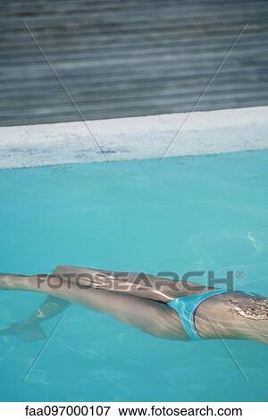 Stock Photo - Woman floating in swimming pool. Fotosearch