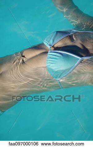 Stock Photograph - Woman floating in swimming pool. Fotosearch
