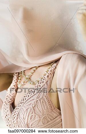 Picture - Woman holding scarf in front of face. Fotosearch