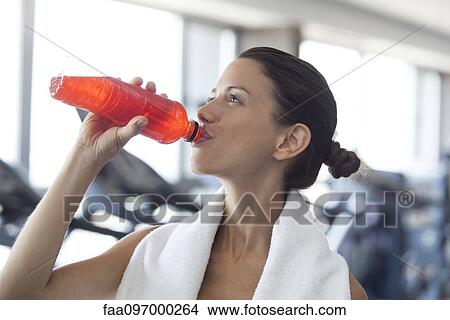 Picture - Woman hydrating after working out. Fotosearch