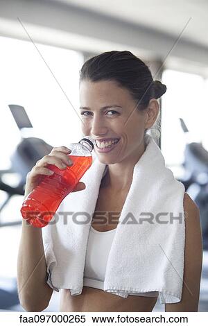 Stock Photography - Woman hydrating with sports drink in health club. Fotosearch