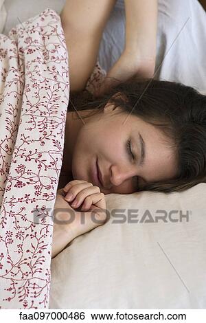 Stock Photograph - Woman relaxing in bed, cropped. Fotosearch