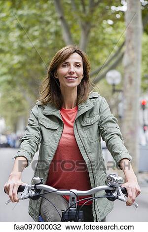 Stock Image - Woman riding bicycle in city. Fotosearch