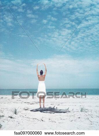 Woman standing on driftwood at the beach, arms raised, rear view View Large Photo Image Stock Image - Woman standing on driftwood at the beach, arms raised, rear view. Fotosearch