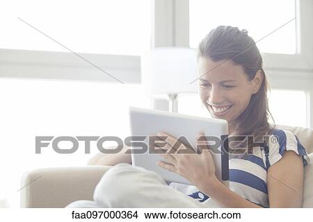 Picture - Woman using digital tablet at home. Fotosearch