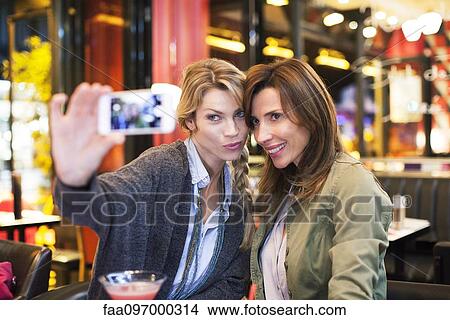 Picture - Women in bar taking self-portrait with photophone. Fotosearch